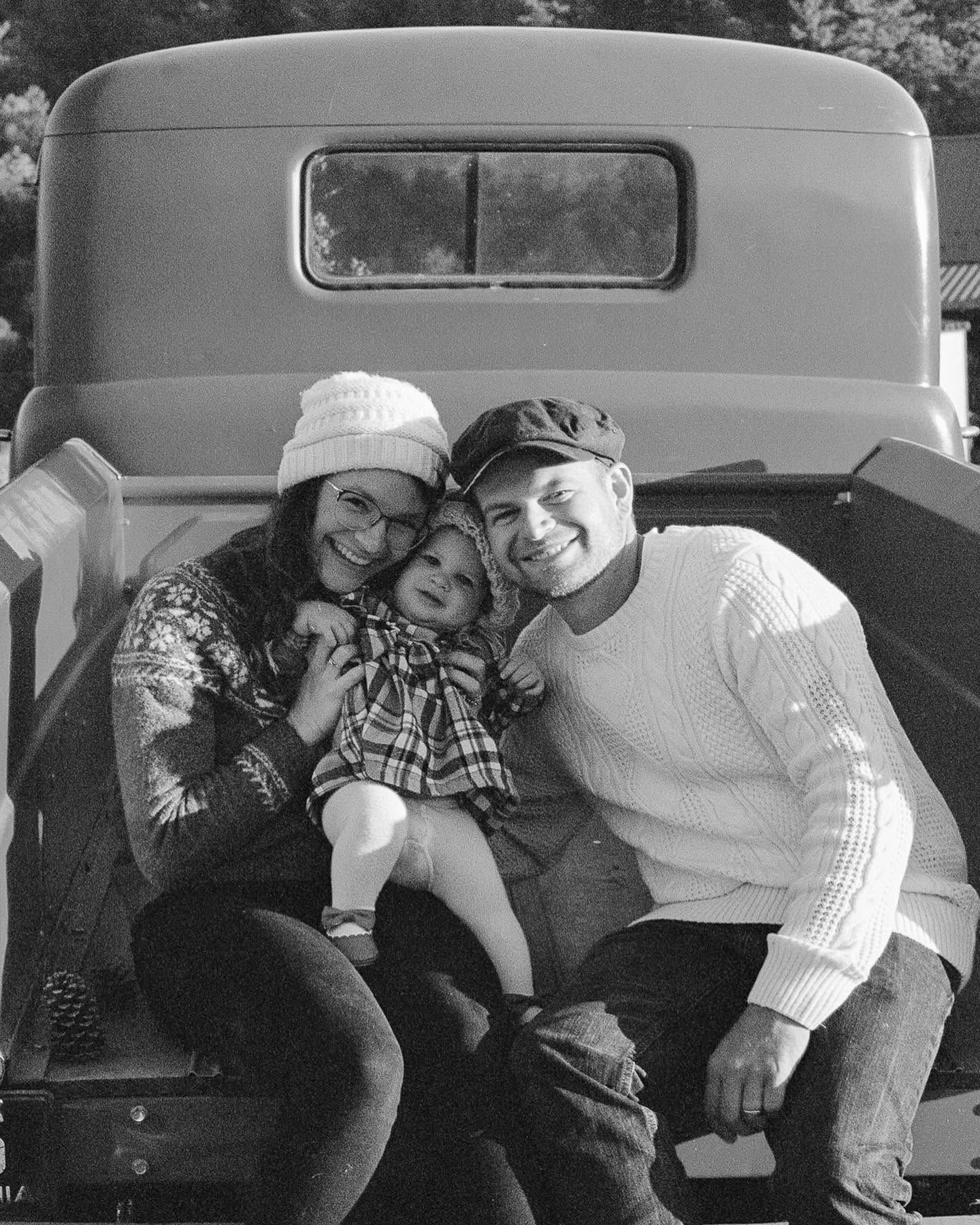 Black-and-white photo of a family with a toddler sitting in the bed of the old pickup